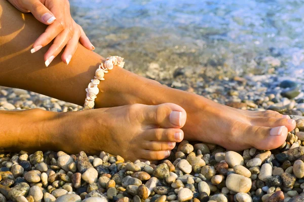 Vrouw voet met de zee schelp armband — Stockfoto