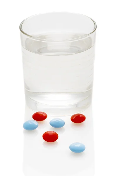 Таблетки и стакан воды — стоковое фото
