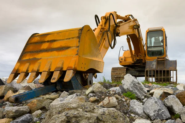 Excavator on heap of stones — Stock Photo, Image