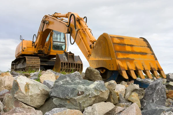Excavator on heap of stones — Stock Photo, Image