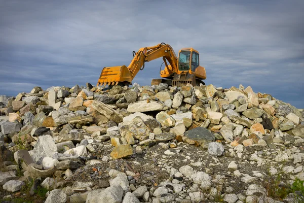 Excavadora sobre montón de piedras — Foto de Stock