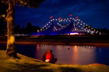 Circus tent with lights and on the bank of river clipart