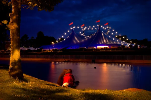 Cirkustält med lampor och på stranden av floden — Stockfoto