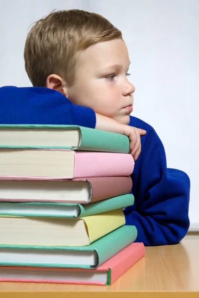 Young boy with hand on top of books — Stock Photo, Image