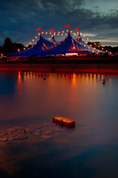 Намет у цирковому стилі з вогнями, відображеними у річці — стокове фото