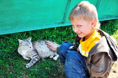 küçük çocuk bir kedi okşayarak