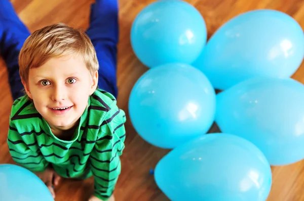 Boy laying on wooden floor with balloons — Stock Photo, Image
