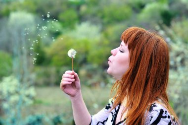 Şişirme Dandelion üzerinde güzel bir kız