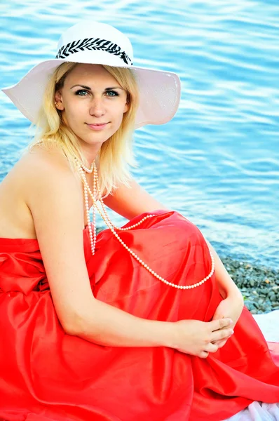 Dáma na sobě červené šaty na pláži — Stock fotografie