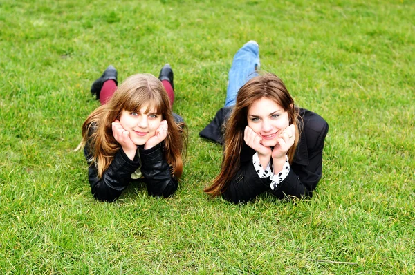 Teen girls laying on the green grass — Stock Photo, Image