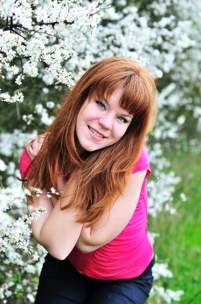 Rödhåriga tjej i blomma trädgård — Stockfoto