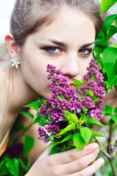 Όμορφο κορίτσι εφήβων μυρίζοντας λιλά άνθη — Φωτογραφία Αρχείου