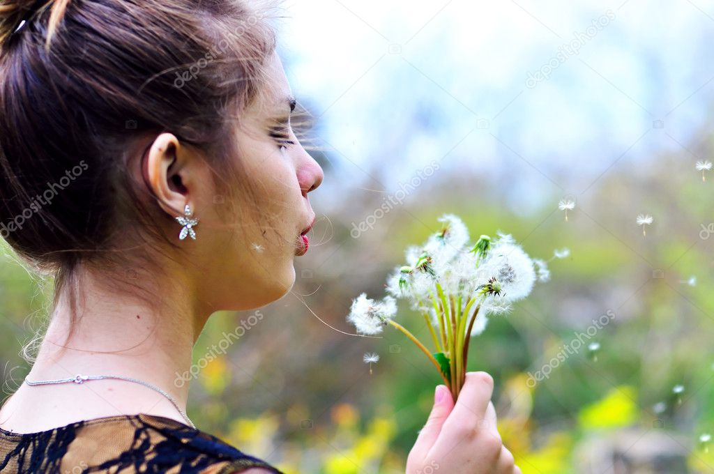Girl blowing on many dandelions