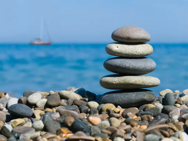 Stack of stones and yacht — Stock Photo, Image