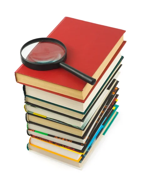 Stack of books and magnifying glass — Stock Photo, Image