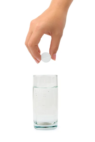 Mão com pílula e vidro de água — Fotografia de Stock