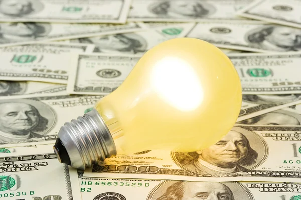 Lighting lamp on money background — Stock Photo, Image
