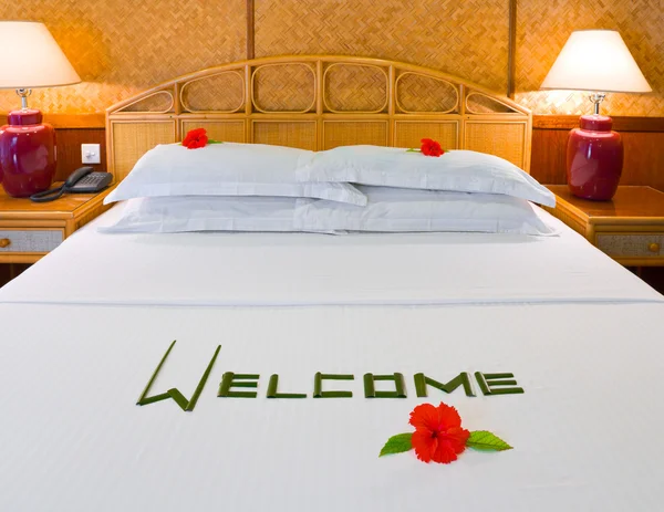 Ordet Välkommen och blommor på sängen — Stockfoto