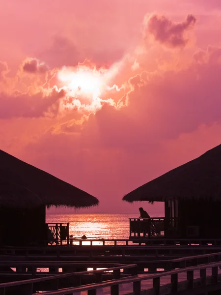Gün batımında su bungalov insan silueti — Stok fotoğraf