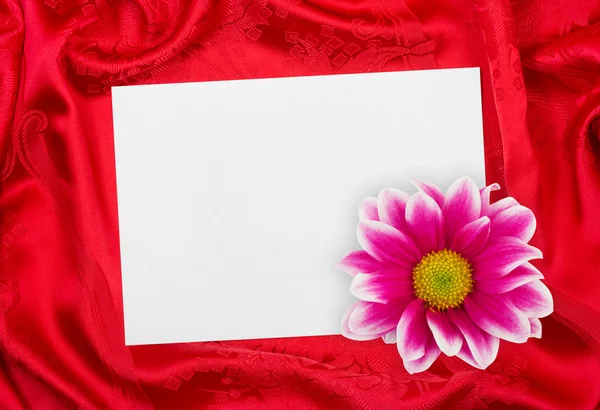 Papper gratulationskort och blomma på rött tyg — Stockfoto
