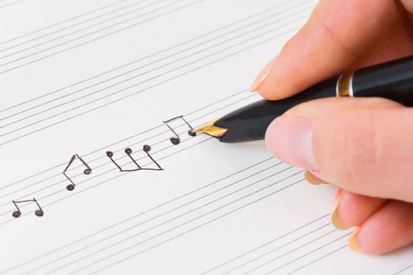 Hand met pen en muziek blad — Stockfoto