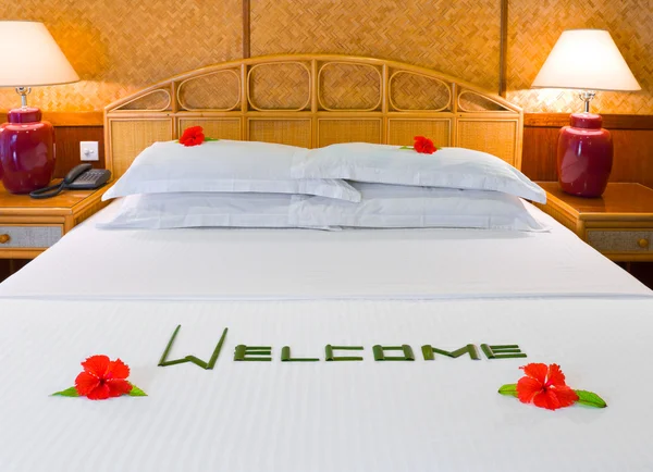Ordet Välkommen och blommor på sängen — Stockfoto