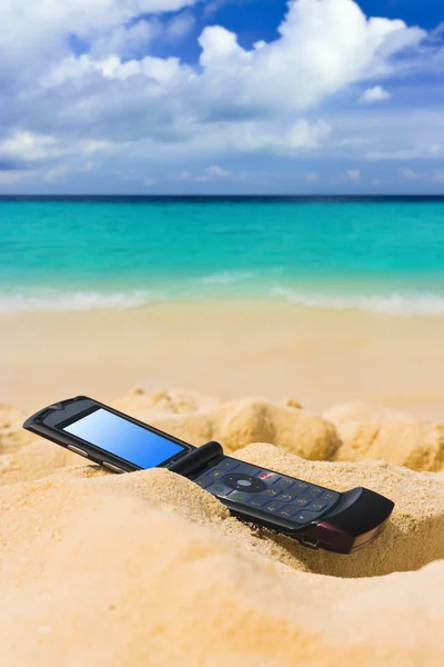 Мобильный телефон на песчаном пляже — стоковое фото
