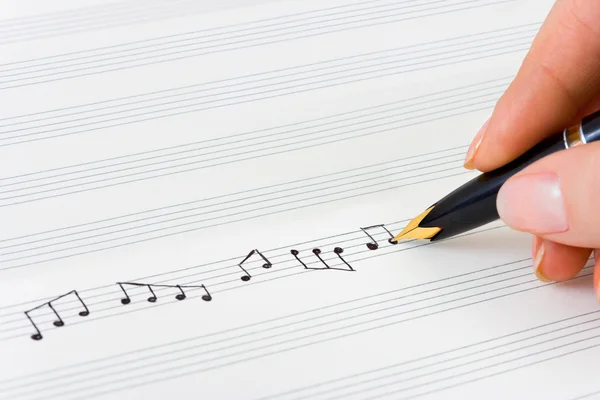 Mão com caneta e folha de música — Fotografia de Stock