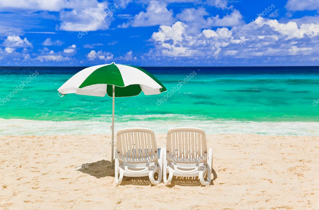 Hermosas sillas de playa con sombrilla en la playa tropical de arena blanca
