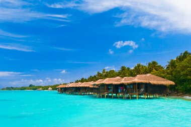 Water bungalows on a tropical island - travel background clipart