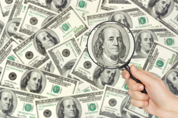 Money and magnifying glass in hand — Stock Photo, Image
