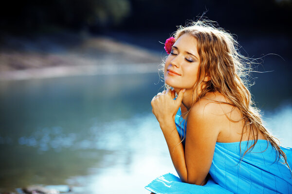 Portrait of young beautiful woman posing near lake