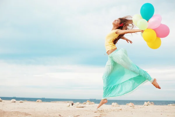 Счастливая девушка с кучей разноцветных воздушных шаров — стоковое фото
