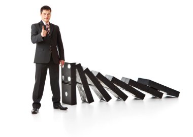 Businessman near a stack of dominoes clipart
