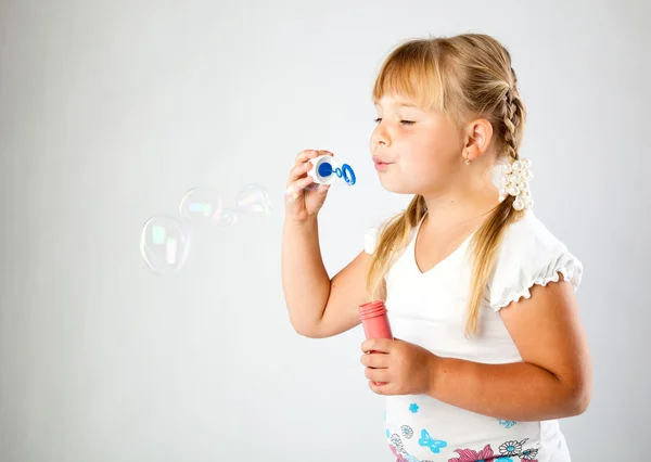 Молодая девушка выдувает мыльные пузыри — стоковое фото