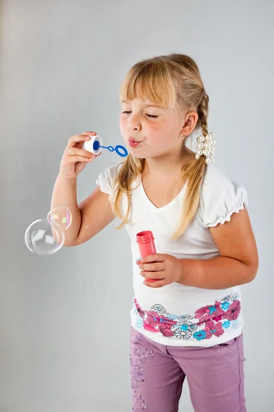 Молода дівчина вибухає мильні бульбашки — стокове фото