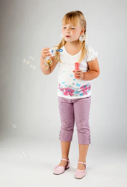 Молода дівчина вибухає мильні бульбашки — стокове фото