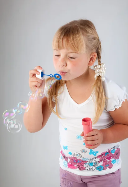 Ung flicka blåsa ut såpbubblor — Stockfoto