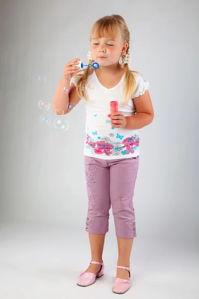 Junges Mädchen pustet Seifenblasen aus — Stockfoto