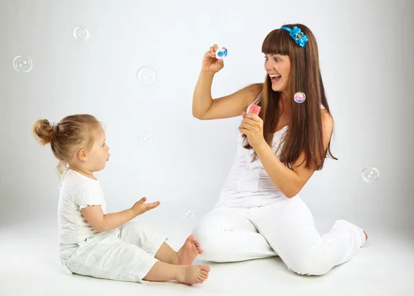 Маленькая девочка и ее мать пускают пузыри — стоковое фото