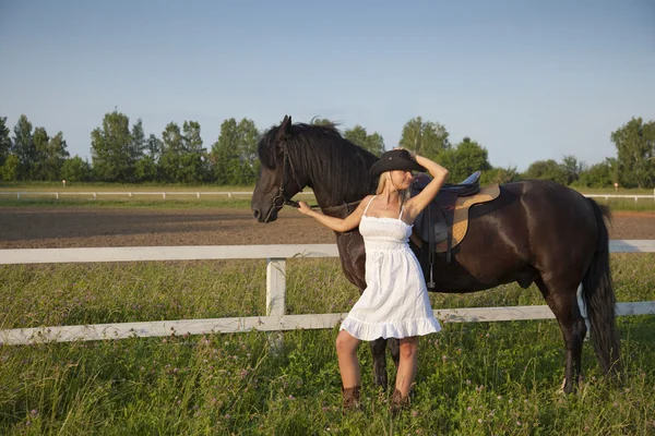 Young blond woman in white dress with horse — Stockfoto
