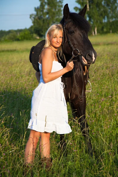 Young blond woman in white dress with horse — Stockfoto