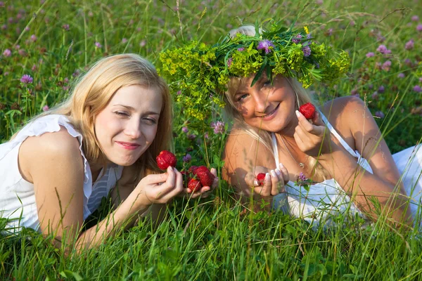 Zwei junge blonde Frauen essen Erdbeeren — Stockfoto