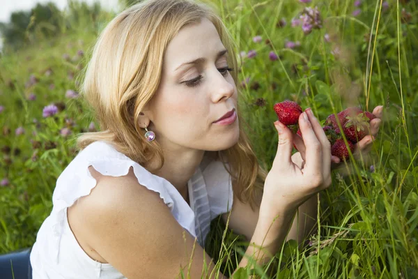 Νεαρή ξανθιά γυναίκα τρώει φράουλες — Φωτογραφία Αρχείου