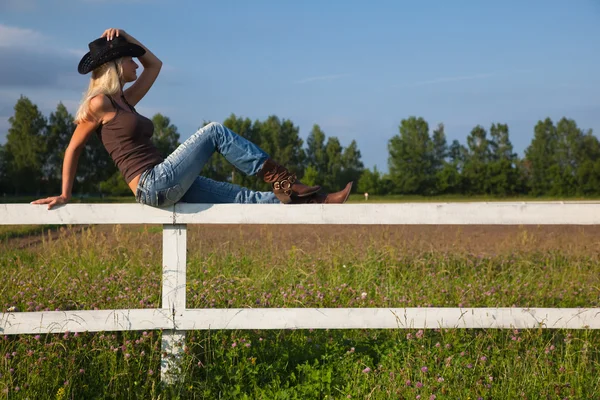 Jovem vaqueira sentada em uma cerca — Fotografia de Stock