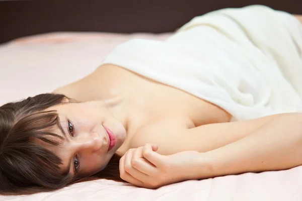 Chica joven está acostada en una cama — Foto de Stock