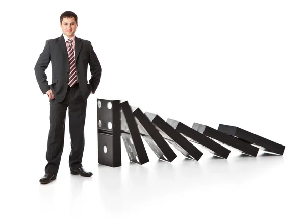 Üzletember közelében egy halom dominó — Stock Fotó