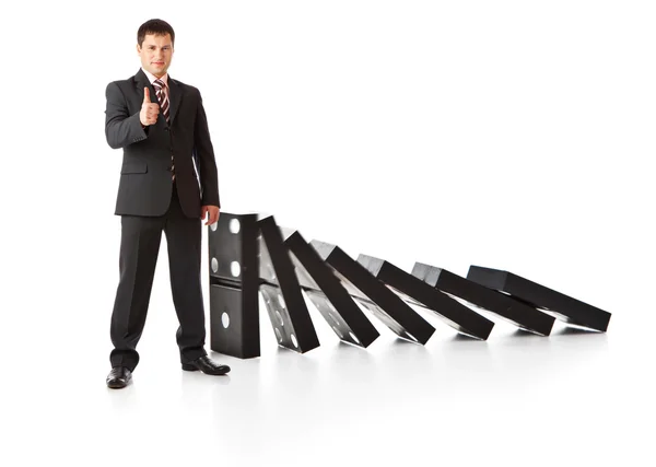 Üzletember közelében egy halom dominó — Stock Fotó