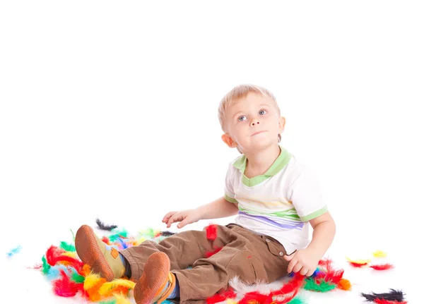 Malý chlapec sedí na toku s peřím — Stock fotografie