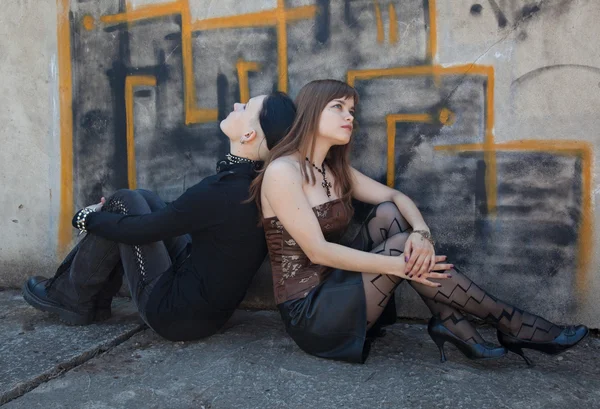 Meninas sentadas na frente da parede de grafite — Fotografia de Stock